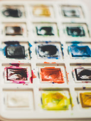 Set of an used watercolor paint in white case, closeup.