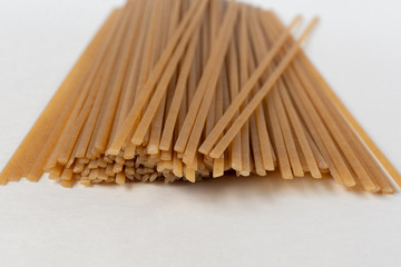 Long flat brown macaroni on a white background.