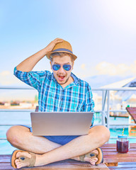 Concept of relaxing at sea. The man is working on time. The amazing face of the worker, in the computer. Shocked
