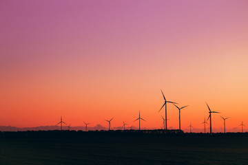 Wind turbines against beautiful sunset sky. Eolic park. Eco farm of clean energy.