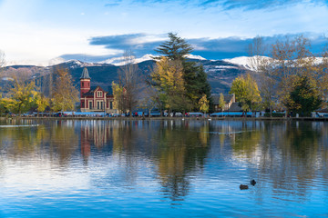 Fototapeta na wymiar Puigcerdà, Catalonia / Spain. Lake of Puigcerdà with Villa Paulita and the snowy Pyrenees in the background