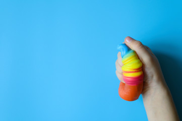 anti stress squishy toy in the form of multicolored ice cream in children's hands on blue background. space for text