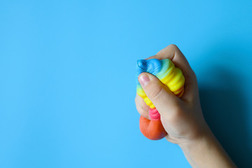 anti stress squishy toy in the form of multicolored ice cream in children's hands on blue background. space for text - obrazy, fototapety, plakaty