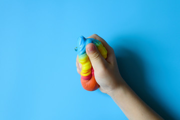 anti stress squishy toy in the form of multicolored ice cream in children's hands on blue background. space for text