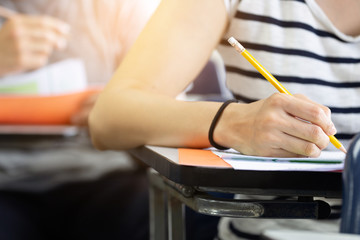 high school,university student study.hands holding pencil writing paper answer sheet.sitting lecture chair taking final exam attending in examination classroom.concept scholarship for education abroad