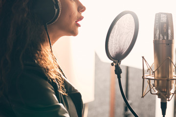 Pretty female singer recording in music studio