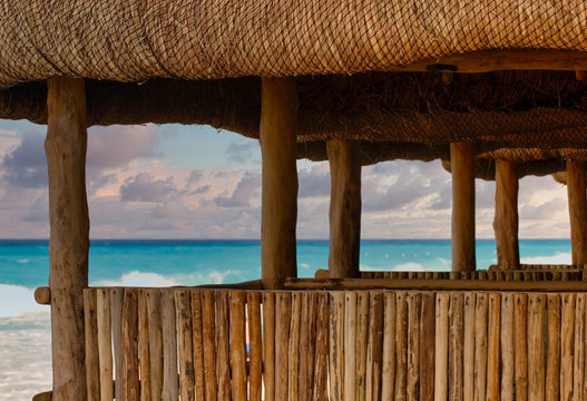 A bamboo and straw thatched hut on the beach with the ocean and surf in the background
