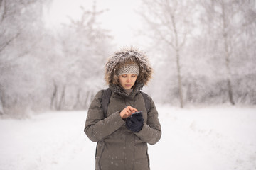 Fototapeta na wymiar Woman texting on mobile phone during snowfall
