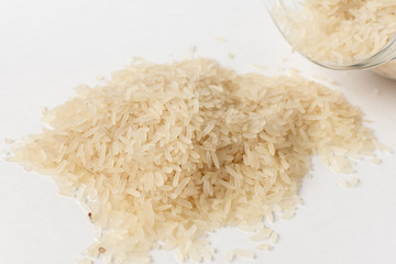Long white rice on a white background. Spilled from a jar.
