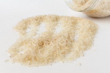 Long white rice on a white background. Spilled from a jar.