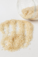 Long white rice on a white background. Spilled from a jar.