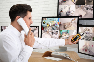 Male security guard talking by telephone near monitors at workplace
