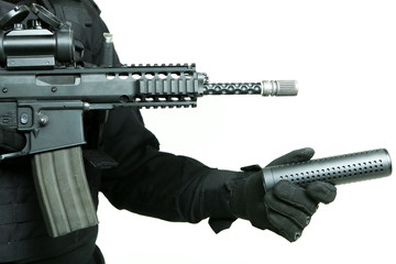 gloved hand of a man attaches a silencer to the barrel of a machine gun