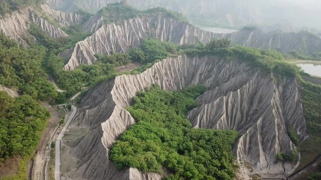 Tilt Up Aerial View on Amazing Grey Mudstone Cliffs and Green Forest on Taiwan Island, Tianliao Moon World Landscape Park