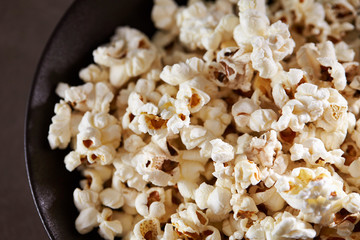 Popcorn in black bowl on black background 