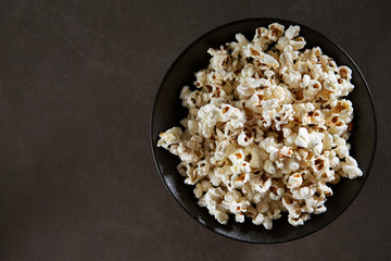 Popcorn in black bowl on black background 