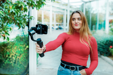 adult girl dressed in red, videotaping herself with her mobile phone, lifestyle concept