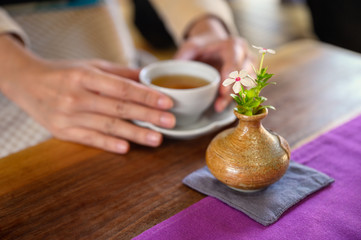 Female hands holding a hot tea on wooden table