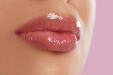 Young woman with beautiful full lips on pink background, closeup