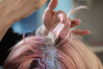 Hairdresser colorist dyes the hair of a woman to a client in different colors.