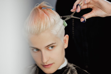 Obraz premium Hairdresser machine cuts woman client. A short haircut, shaved temple and a drawing on the hair.