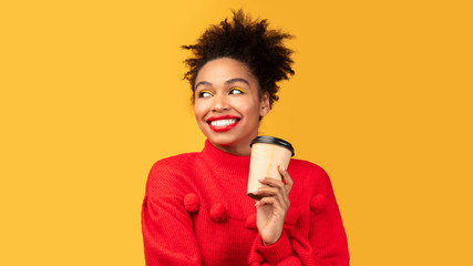 Happy afro woman holding coffee mug at studio