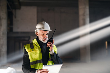 Man engineer using walkie talkie on construction site. - obrazy, fototapety, plakaty