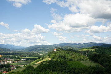 Fototapeta na wymiar City of Maribor in Slovenia is surrounded by Kalvarija hill and nature. Blue sky with cloud as large copy space