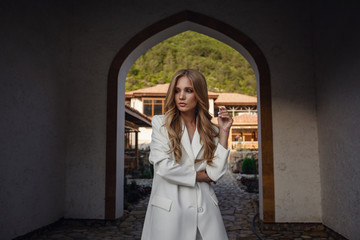 Outdoor full body fashion portrait of fashionable woman in white suit posing in street of east city