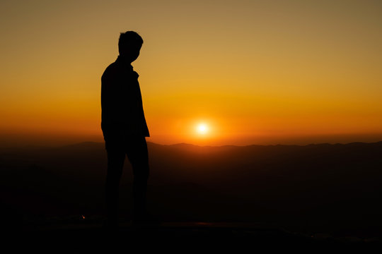 Image of Silhouette man standing during sunset on highest mountain.