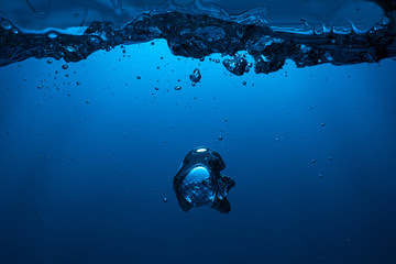 large air bubbles float into the blue light from the dark