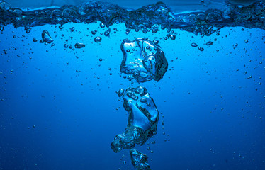 large air bubbles float into the blue light from the dark