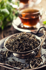 Dried tea leaves in bowl on rustic wooden table