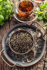 Dried tea leaves in bowl on rustic wooden table
