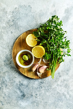 Fresh parsley, lemon, garlic and olives on a wooden kitchen board. Natural food ingredients. Symbolic image