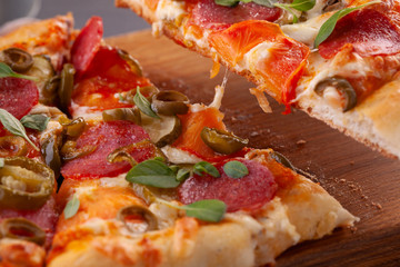 Homemade spicy pepperoni pizza and cooking ingredients. Pepperoni pizza on a gray wooden table.