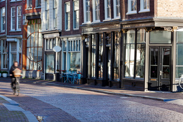 Cobblestones street with historical buildings and a motion blur cyclist in Dordrecht in the Netherlands