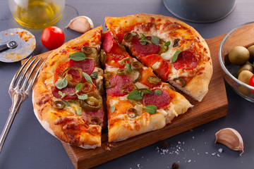 Homemade spicy pepperoni pizza and cooking ingredients. Pepperoni pizza on a gray wooden table.