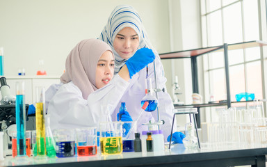 A Asian female medical or scientific researcher or doctor using looking at a test tube of clear...