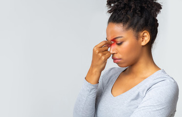 Sad young woman touching her nose bridge