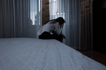 Fototapeta na wymiar Sad young woman sitting on the bed in the bedroom, People with depression concept.