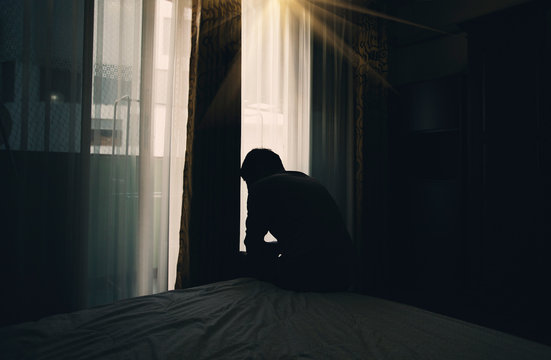 Sad young man sitting on the bed in the bedroom, People with depression concept. - Powered by Adobe