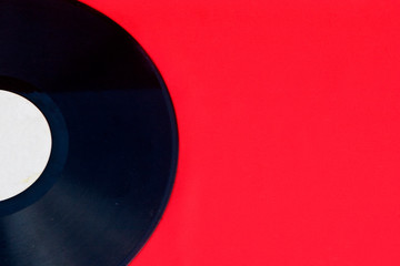 Vanilla plate on a red background close-up. Musical plate with scratches from an old gramophone. Close-up retro photo