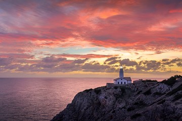 Far de Capdepera lighthouse, sunrise with beautiful colourful sky and lighthouse light beam, Cala Ratjada, Mallorca, Spain.