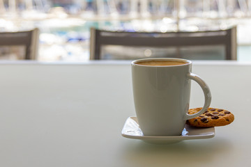 A cup of cappuccino cofee with cookie on a saucer. Copy space. Light background