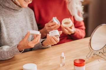Two good-looking elderly women holding new creams