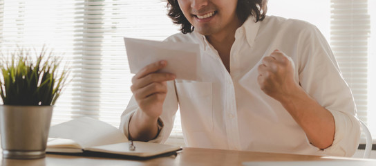 panoramic banner. happy young asian employee business man holding money bonus card in paper...