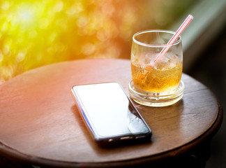 Fototapeta na wymiar Glass of iced tea with straws and mobile phone on circle wooden table. Relax concept.