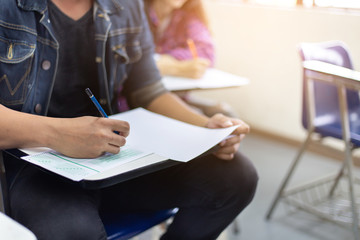 high school,university student study.hands holding pencil writing paper answer sheet.sitting lecture chair taking final exam attending in examination classroom.concept scholarship for education abroad