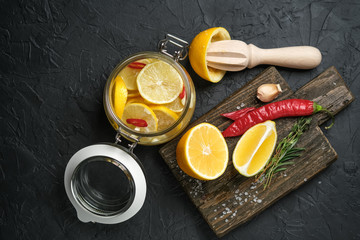 Salted lemons in glass jar with ingredients on a dark background. Moroccan cuisine.